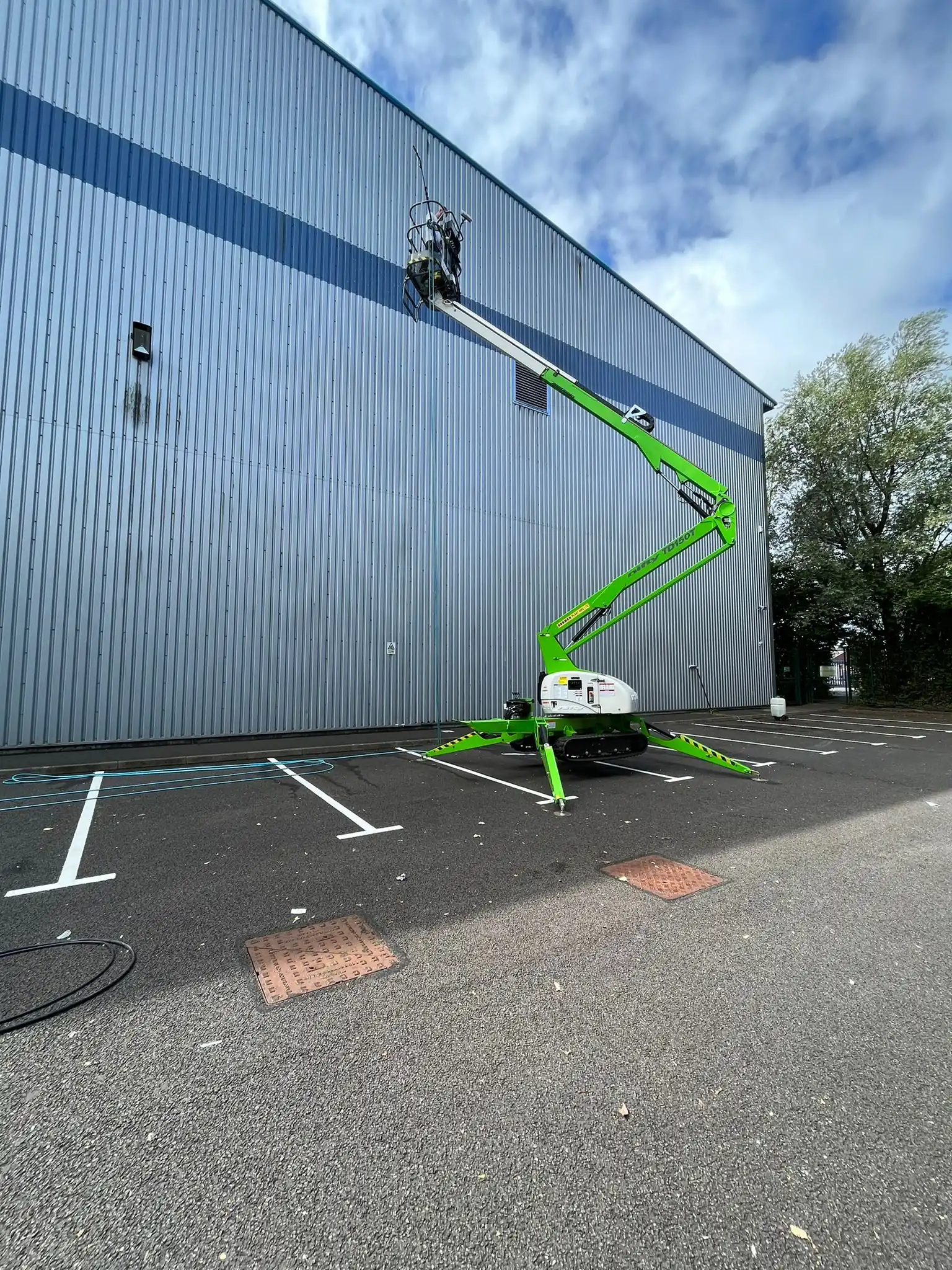 Spider lift cleaning ribbed metal cladding on an industrial unit