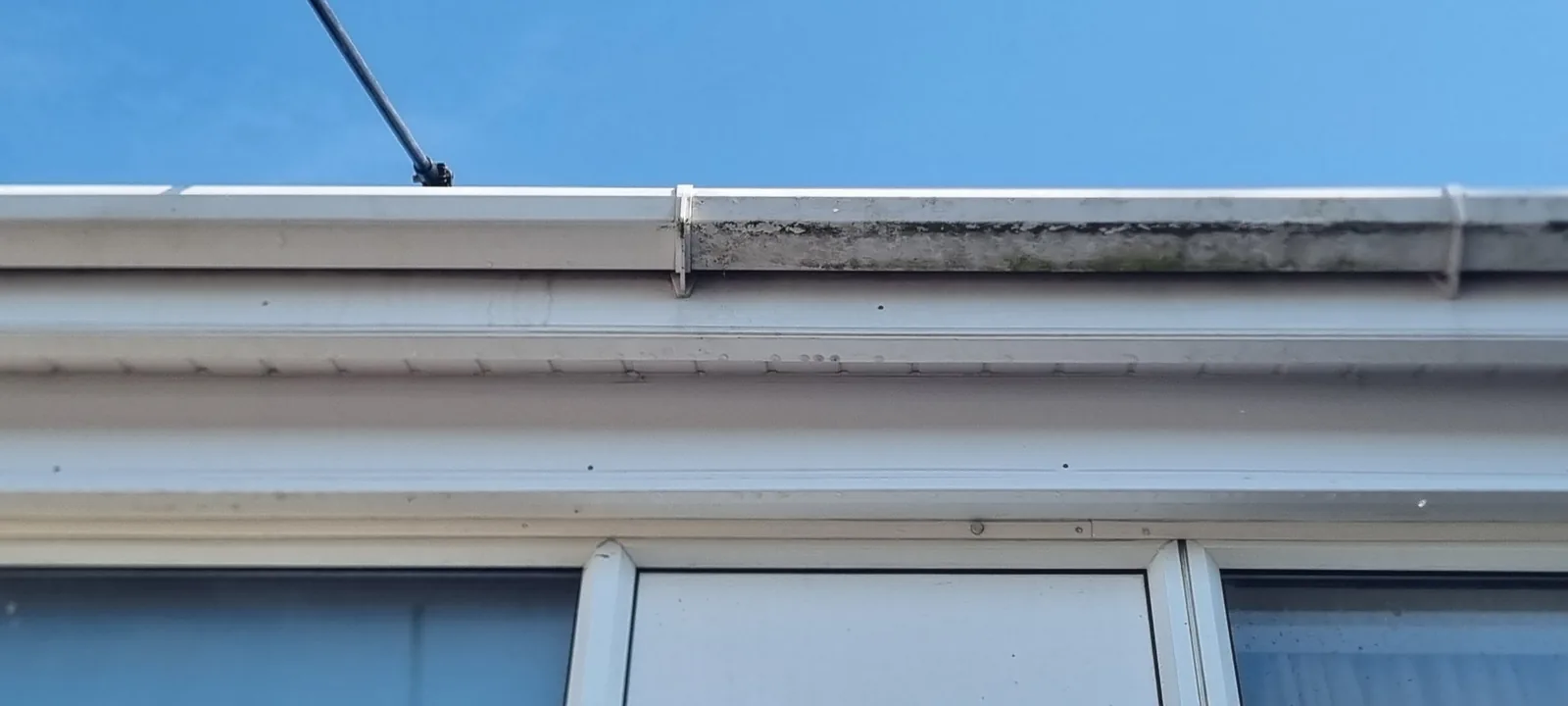 Fascia cleaning in progress showing the clear contrast between cleaned bright white UPVC and the dull, dirty section still to be done