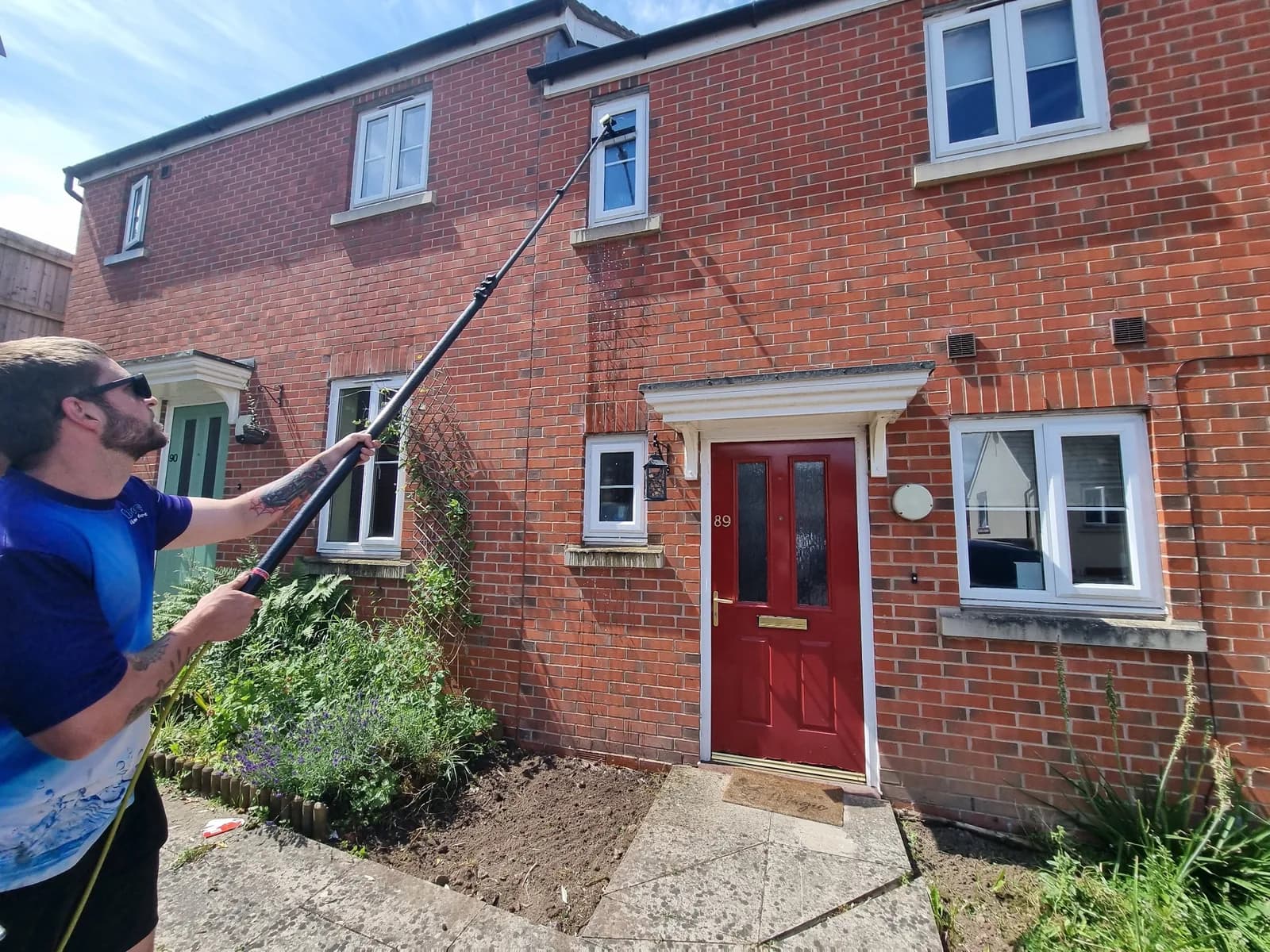 Access Window Cleaning technician using a water fed pole to clean residential windows