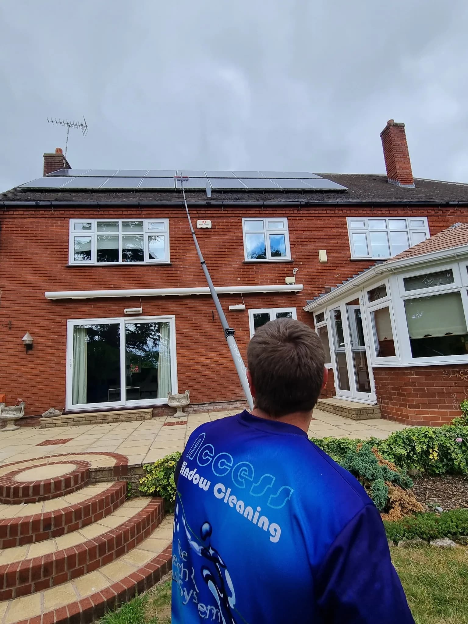 Access Window Cleaning technician cleaning residential solar panels with a water fed pole